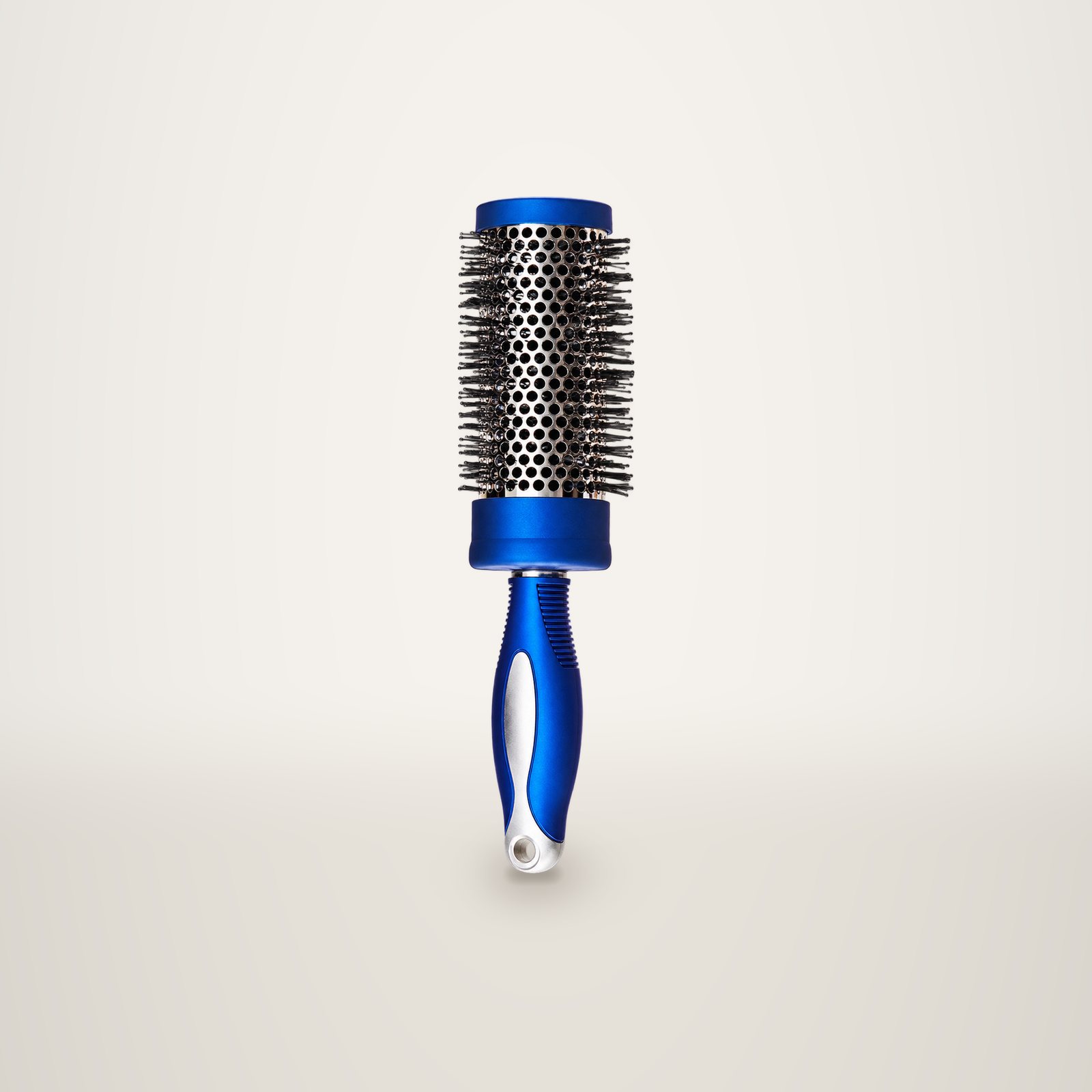 Une brosse ronde à manche bleu et cylindre métallique perforé, posée sur un fond de studio crème.